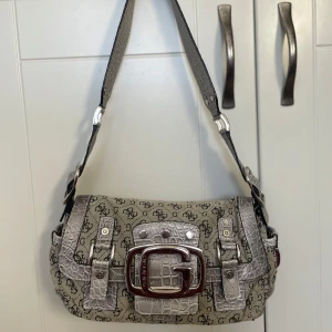 Vintage Väska - En fin vintage väska! Äkta Guess, säljes då ej kommer till användning längre och inte min stil. Har en blå fläck på undersidan men annars i bra skick för vintage!