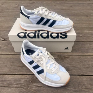 Adidas sneakers med svarta ränder - Säljer ett par helt oanvända Adidas Run 70s 2.0 sneakers med klassiska tre ränder på sidorna. Skorna är superlätta och mjuka. 