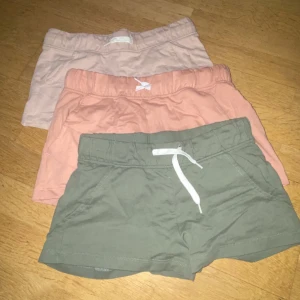3-pack shorts i olika färger - Tre par mjuka shorts i bomull, perfekta för sommaren. Färgerna är ljusrosa, persikofärgad och olivgrön. Alla har resår i midjan och snörning framtill för skön passform. Snygga och enkla att matcha till olika toppar, eller bara mysa hemma 