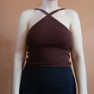 Brun topp - Brun topp från Gina Tricot med korsade axelband framtill. Tyget är ribbat och färgen är som de första två bilderna. Endast provad och superfint skick. Storlek XS, men stor i storlek och passar mig som bär S ☺️