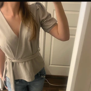Beige omlottblus  - Jätte söt blus. Lånade bilder då den ej passade mig. Köpt på SALT men märket är sisters point.