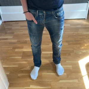 Replay anbass hyperflex - Säljer ett par klassiska blå jeansbyxor från Replay med snygga slitningar och raka ben. Jeansen har fem fickor, dragkedja och knapp i midjan samt diskret Replay-logga på bakfickan.