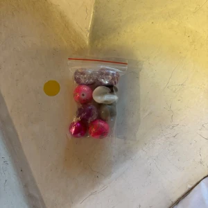 Mixade pärlor i olika färger och former - En påse med mixade pärlor i olika färger som rosa, lila och vitt. Pärlorna har både glittriga och enfärgade ytor och varierar i form och storlek. Perfekt för att skapa egna smycken eller pysselprojekt.