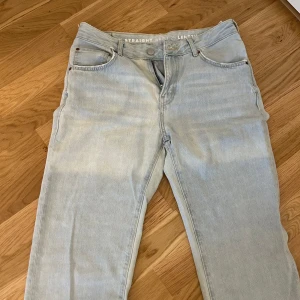 Ljusblå jeans med rak passform - Säljer ett par ljusblå jeans med låg midja och rak passform. Jeansen har klassisk femficksdesign och bälteshällor. Midjemått är 29 och längd 32. Perfekta för en avslappnad stil.