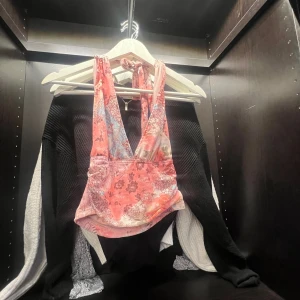 Rosa blommig linnetopp - Säljer en söt rosa linnetopp med blommigt mönster och djup v-ringning. Toppen har smala axelband och är croppad i modellen, perfekt för varma dagar.