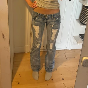 Lågmidjade bootcut vintage jeans - Lowwaist bootcut vintage jeans med ribbade hål. Supersnygga i superskick! Har till och med alla diamanter kvar trots vintage! Står att det är stl 32 men dom sitter som S/M. Ända defekten är att pyntet på en knapp saknas därav billigt pris❤️hör av er för frågor eller bilder!❤️
