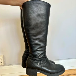 Höga boots - Ett par svarta skinn stövlar i storlek 41. De är knähöga och har dragkedja på insidan. 