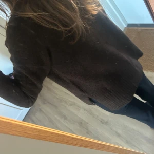 Mörkbrun stickad tröja - Mysig mörkbrun stickad tröja med rund hals och långa ärmar. Tröjan har en rak passform och breda ribbade muddar vid ärmslut och nederkant. Aldrig andvänd 