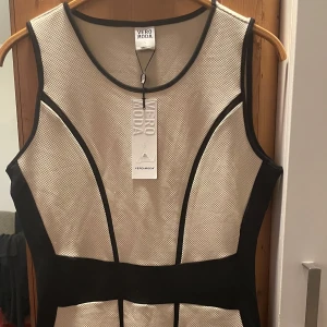 *NY*Ljusbeige/svart klänning från Vero Moda i stl L  - Säljer en snygg ärmlös klänning från Vero Moda i beige med svarta kontrastpaneler. Klänningen har rund halsringning och figurnära passform, perfekt för dig som vill sticka ut med stilrena linjer. Ny med prislapp.  Finns två små tråddragningar längst ned (se sista bilden) du bestämmer om du vill dra in de/klippa bort de, inget som syns. Normal i stl.  Nypris: 349,95 sek, Pris nu: 50 sek