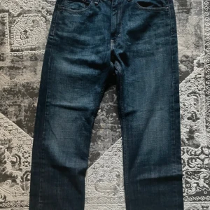 Levi's 505 mörkblå jeans - Klassiska mörkblå Levi's 505 jeans med rak passform och fem fickor. Jeansen har dragkedjegylf och tydliga kontrastsömmar. Perfekta för dig som gillar tidlös denimstil.