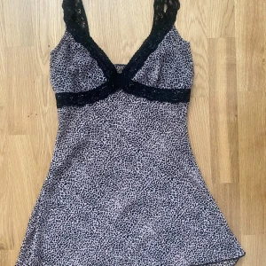 Leopardmönstrad topp med spetsdetaljer - Säljer en snygg topp med leopardmönster och svarta spetsdetaljer vid axelband och byst. Toppen har en figurnära passform upptill och lätt utsvängd. Köpt på en vintage butik dock utan lapp. 