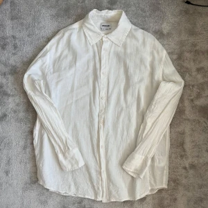 Vit linneskjorta - Säljer en klassisk vit skjorta i linne från Weekday. Skjortan har lång ärm, knappar framtill och en avslappnad passform. Perfekt för en stilren och enkel look.