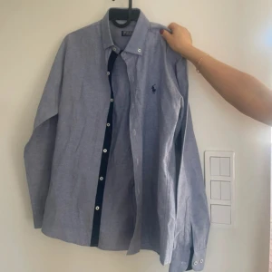 Blå skjorta från Polo Ralph Lauren - Klassisk blå skjorta från Polo Ralph Lauren, perfekt till en stilren look. Materialet känns mjukt och svalt. Skick 9/10 inget fel, perfekt nu till sommaren!  Storlek M
