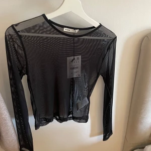 Svart meshtröja från Pull&Bear - Säljer en svart, transparent meshtröja från Pull&Bear. Tröjan har lång ärm och rund halsringning, perfekt att styla lager på lager. Enkel och stilren design som passar till många olika looks. Aldrig använd.