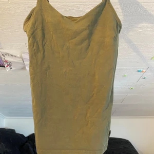 Olivgrön linnetopp från 157 - Säljer en enkel olivgrön linnetopp från 157 med smala axelband och v-ringad hals. Toppen är tillverkad i bomull med lite elastan för extra stretch och komfort. Perfekt att matcha med jeans eller shorts.