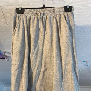 Grå långkjol med resår från Kappahl - Enkel och skön grå långkjol från Kappahl med resår och dragsko i midjan. Kjolen har fickor på sidorna och är gjord i mjukt bomullsmaterial. Perfekt för en avslappnad stil.