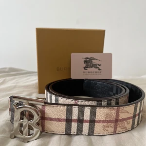 Burbery bälte med silver - 115 cm. Snyggt bälte från Burbery med rutigt mönster i beige, svart, vitt och rött. Helt oanvänd och ren. Perfekt accessoar för att lyfta din outfit. PRISET KAN DISKUTERAS.