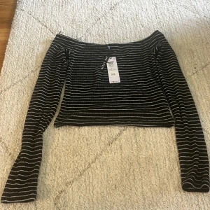 Svart offshoulder topp med vita ränder - Säljer en svart offshoulder topp med vita ränder. Toppen är endast provad med prislapp kvar. Storlek s.