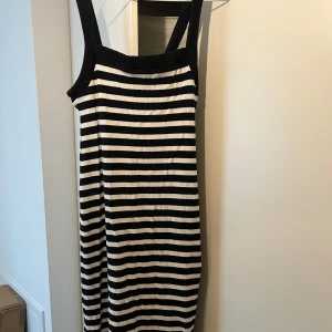 Randig ribbad klänning med breda axelband - Svartvit ribbad klänning med breda axelband och raka linjer. Klänningen har ett klassiskt randigt mönster och är figurnära med stretchigt material. Strl S 