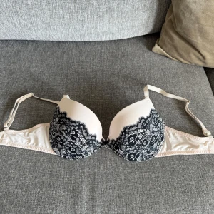KappAhl push-up bh, storlek 80C. Ny - *Vacker behå i beige med mönster av svart spets. *Justerbara axelband och hyskna och hake stängning bak. *Behåen har en mjuk och bekväm passform. Aldrig använd, endast tvättad. Perfekt för dig som vill ha en feminin och elegant look. *80 C *Djurfritt och rökfritt hem.