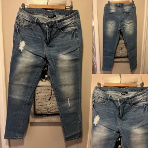 Blå jeansbyxor från KappAhl - Snygga blå jeansbyxor från KappAhl med slitna detaljer på låret och benet. Klassisk femficksmodell med knapp och dragkedja framtill. Ljus tvätt och raka ben ger en avslappnad look. Knappt använd i jättefint skick.