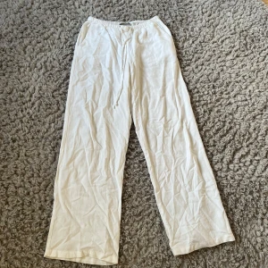 Vita linnebyxor från Gina Tricot - Säljer ett par vita linnebyxor från Gina Tricot i storlek XXS. Byxorna har resår i midjan med dragsko och raka, vida ben. Perfekta för varma dagar och en avslappnad stil. De är i bra skick men tyvärr för korta för mig
