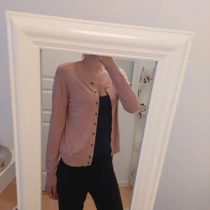 Ljusrosa kofta från H&M - Säljer en ljusrosa kofta från H&M Basics. Koftan har långa ärmar och knappar framtill. Perfekt att slänga över en topp eller t-shirt för en enkel och stilren look. Är storlek L men passar även M