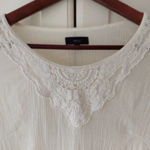 Vit/gräddvit blus med spetsdetaljer från Minus - Säljer en romantisk vit/gräddvit blus från Minus med lång ärm och vacker spetsdetalj i halsen. Blusen har en lätt och luftig känsla, perfekt för vår och sommar. Fina spetskanter längs ärmarna ger en extra touch.