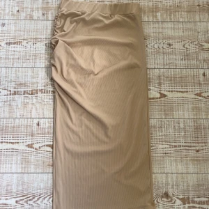 Kjol från nelly - Medellång beige kjol från nelly med scrunch och slits i storlek xs. Köpt för länge sen men fint skick då jag knappt användt den🥰