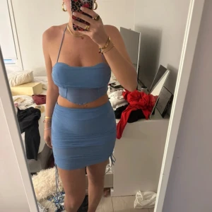 Ljusblå tight kortklänning  - Säljer en ljusblå tight kortklänning med öppen rygg. Klänningen har en croppad topp och en figurnära kjol, perfekt för sommarens tillfällen. Materialet känns mjukt och stretchigt.