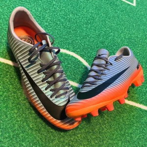 Nike Mercurial cr7 - Säljer ett par Nike Mercurial fotbollsskor i metallic silver med svarta detaljer och orange sula. Skorna har snörning och är designade för spel på konstgräs eller gräs. Perfekta för dig som vill ha lätta och snygga skor på planen.