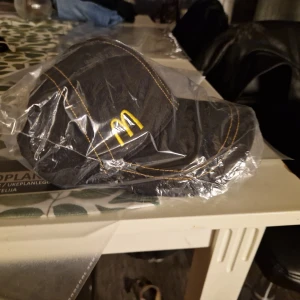Svart keps med McDonald's-logga - Svart keps med tydliga gula sömmar och broderad McDonald's-logga framtill. Klassisk modell med böjd skärm, tillverkad i bomull. Perfekt för dig som gillar streetwear eller vill ha något unikt.