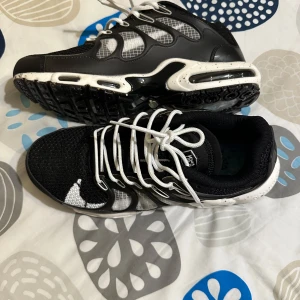 Svarta och vita sneakers från Nike - Säljer ett par snygga svarta och vita Nike sneakers med vit sula och svarta detaljer. Skorna har ett sportigt utseende med meshpaneler och vita snören. Perfekta för dig som gillar streetstyle och vill ha bekväma skor till vardags.