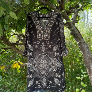 Svart kortklänning med mönster - Supersnygg svart kortklänning från Odd Molly med unikt vitt och beige mönster över hela klänningen. V-ringad hals, trekvartsärm och flowig passform. Perfekt för dig som gillar boho-vibe och detaljerade prints. Storlek 2 som enligt deras storleksguide motsvarar en storlek M.  Mycket fint skick, jag hittar inga synliga anmärkningar eller defekter.