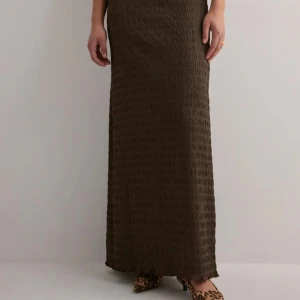 Maxi skirt från Nelly  - Säljer en brun maxi långkjol snygg strukturerad yta. Perfekt att ha på sig under fester och sommaren. Det är storlek S men passar också som M. 