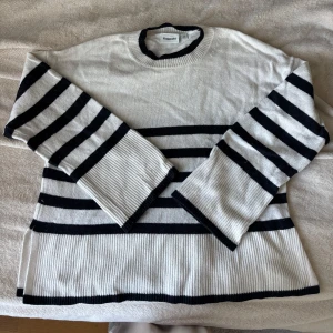 Randig stickad tröja från Kappahl - Vit och svart randig stickad tröja från Kappahl med breda ribbade muddar och slits i sidorna. Tröjan har långa ärmar!!