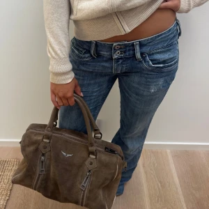 Zadig & Voltaire handbag - Zadig handväska/liten dufflebag. I brun mocha. Väl använd så skavanker förekommer. Kommer med långa band till väskan också. Bild 4 och 5 visar att en av hylsorna till långa banden håller på att åka av och att det kommit rosa fläckar från en highlighter i väskan. Nypris cirka 6000 sek. 