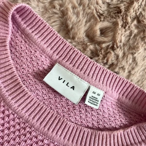 Ljusrosa stickad tröja från Vila - Supersöt ljusrosa stickad tröja från Vila i storlek XS men lite liten i storleken. Tröjan har rund halsringning, långärmade ärmar och ett snyggt strukturerat stickmönster. Perfekt för dig som gillar en enkel men ändå trendig look. Tröjan har två maskor men som säkert går att fixa till! Annars bra skick.