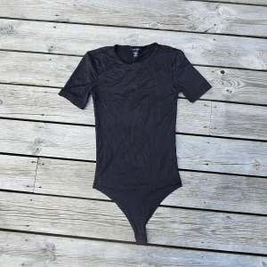 Svart body - En svart t-shirt body från Amisu i storlek XS, använd endast nån gång. Jätte fint skick! Dubbeltyg så är inte det minsta genomskinlig ❤️🙏🏻 - finns en likadan i vitt upplagd med 