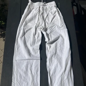 Vita linnebyxor - Snygga vita linnebyxor med bred resår i midjan och snörning framtill. Byxorna har raka ben och praktiska fickor på sidorna. Luftigt material som passar bra när det är varmt ute.🤍