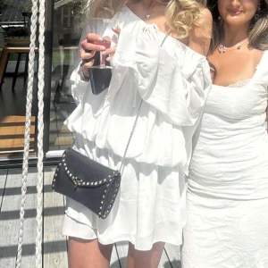 Vit offshoulder klänning designbysi  - Superfin vit kortklänning med offshoulder och långa ärmar. Klänningen har volangdetaljer, resår i midjan och knyt framtill. Från designbysi, använd en gång 🤍