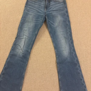 Blå bootcut jeans med broderade bakfickor - Snygga blå jeans med bootcut passform och coola broderade detaljer på bakfickorna. Jeansen är från ginatricot Young och säljs för att de inte kommer till användning längre!