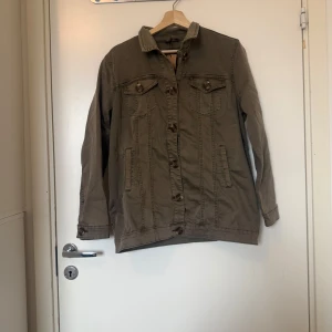 Broderad jeansjacka från Cream - Snygg beige jeansjacka från Cream med unika broderade detaljer i gult, rött och brunt på ryggen. Klassisk krage, knäppning framtill och två bröstfickor med knappar. Perfekt för dig som vill sticka ut med en cool och personlig stil. Storlek 38. Mycket fint skick, jag hittar inga synliga anmärkningar eller defekter. 