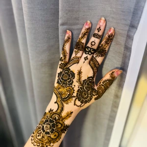 Ekologisk Henna mehndi med blommönster - Snygg henna mehndi med detaljerade blommönster och snirkliga linjer i mörkbrun och guldig ton. Designen täcker handens ovansida och fingrarna med unika, konstnärliga detaljer. Perfekt för dig som vill ha en kreativ och iögonfallande look. Helt naturligt ♥️💖
