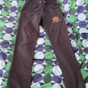 Svarta mjukisbyxor från Gant - Svarta mjukisbyxor från Gant med broderad logga på ena benet. Byxorna har snörning i midjan och två fickor framtill. Sköna och stilrena, perfekta för chill eller träning.