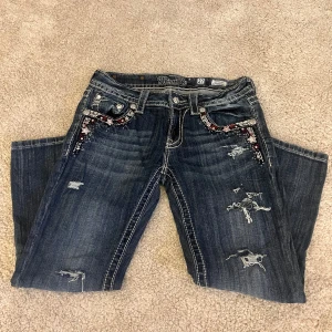 Miss Me jeans med broderade detaljer - Hej, jag säljer dessa blåa Miss Me jeans med slitningar och broderade detaljer i rött, vitt och svart vid fickorna. 💕Jeansen är raka och är ett par trekvartsbyxor (kan givetvis sys om till shorts). Jeansen är från midja ner till häl ca 81 cm långa, innerbenslängden är 20 cm och Mirjam är 35 rakt över (70 runt hela midjan). Jag säljer dessa jeansen då de tyvärr är något för små för mig! 💕Hör av dig om du har fler frågor!💕