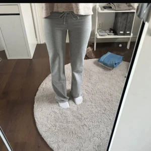 Grå mjukisbyxor med snörning - Säljer ett par grå mjukisbyxor med snörning i midjan. Byxorna har en rak passform och är tillverkade i mjukt material som är perfekt för chill dagar hemma. Snyggt enkla och sköna att bära, passar dig som gillar avslappnad stil.