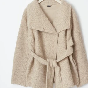 Beige teddyjacka med bälte från Gina Tricot - Säljer en beige teddyjacka från Gina Tricot med bred krage och knytbälte i midjan. Jackan har en mjuk, fluffig yta och långärmade ärmar. Perfekt för dig som gillar en chill och cozy stil under höst och vinter. Pris kan diskuteras😊😊