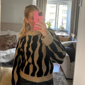Beige och svart stickad zebramönstrad tröja från Mango - Säljer en stickad tröja från Mango med zebramönster i beige och svart. Storlek M men är mer i storlek S då den är liten k storleken! Tröjan är i bra skick, inga defekter! 