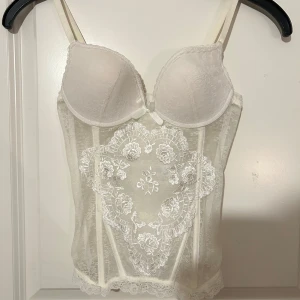 vit spetskorsett  - superfin vit korsett med tunna axelband, vadderade kupor och detaljerad blommig spets framtill🤍köpt på plick! storlek 70c